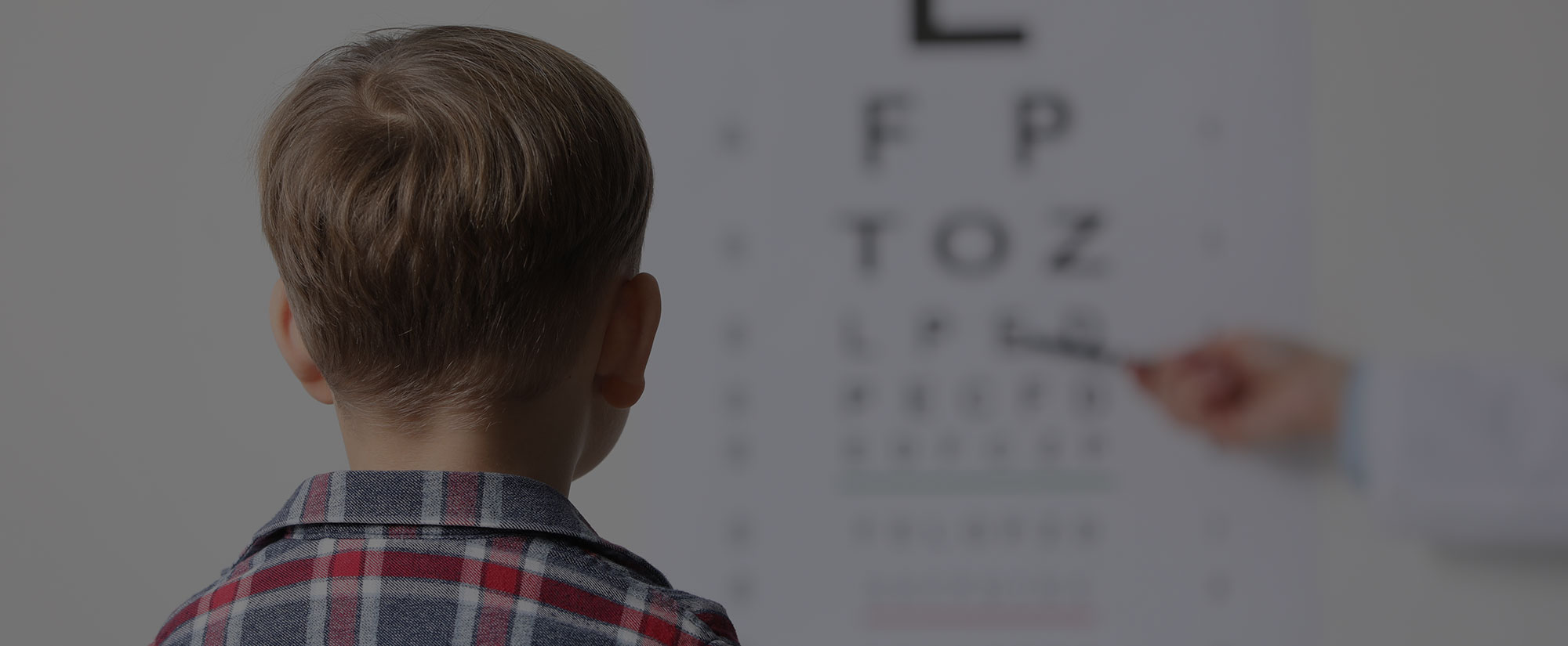 Eye doctor pointing to an eye chart during a young boy's eye exam